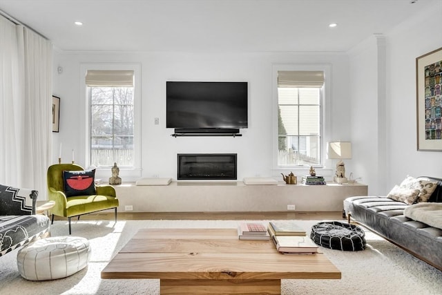 living area with a glass covered fireplace, recessed lighting, and ornamental molding