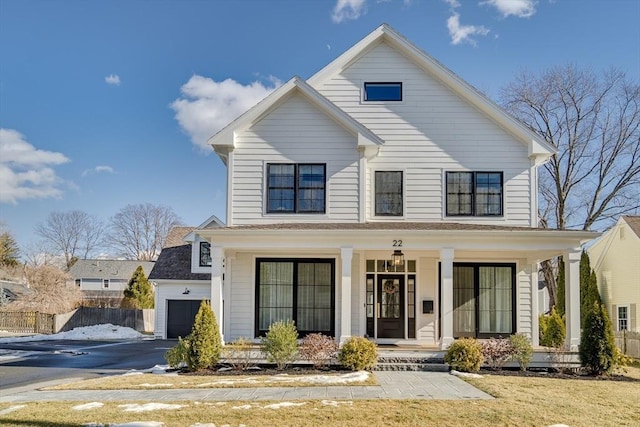 modern farmhouse style home featuring aphalt driveway, covered porch, and fence