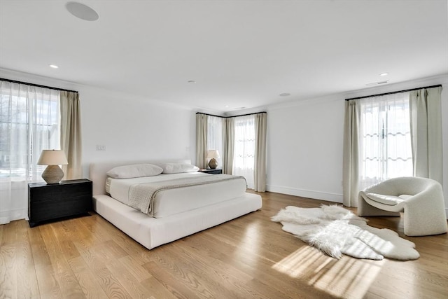 bedroom featuring baseboards, multiple windows, and light wood-style flooring