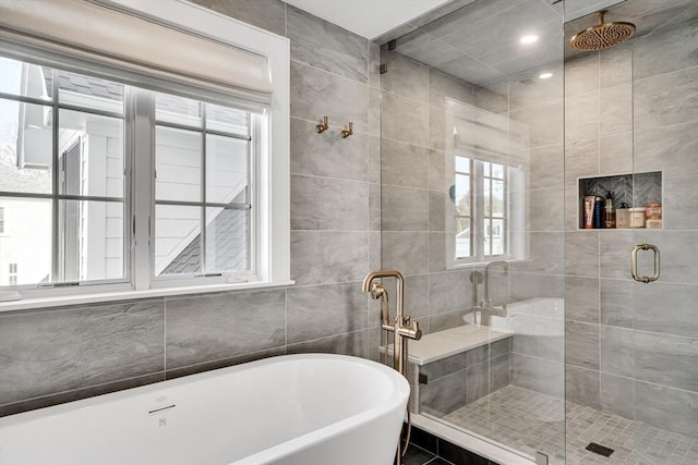 full bathroom with tile walls, a freestanding tub, and a stall shower