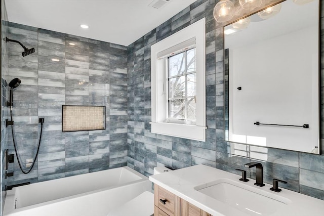 bathroom with vanity, visible vents,  shower combination, decorative backsplash, and tile walls