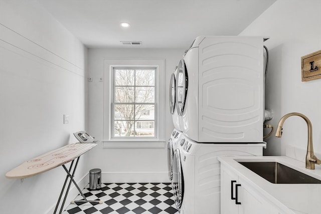 laundry area with visible vents, tile patterned floors, cabinet space, stacked washer / drying machine, and a sink