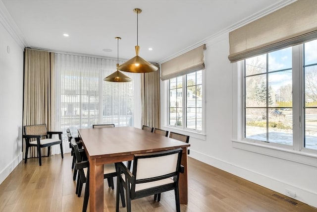 dining area with baseboards, light wood-style floors, visible vents, and ornamental molding