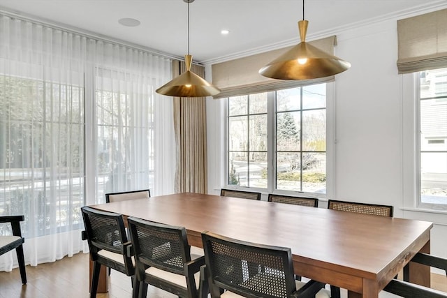 dining space with light wood-style flooring and ornamental molding