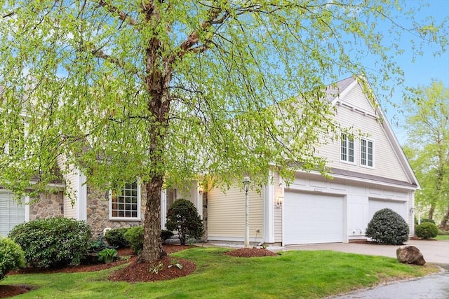 obstructed view of property with concrete driveway, a front lawn, and an attached garage