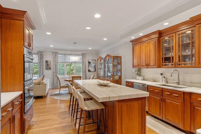 kitchen featuring a sink, ornamental molding, light countertops, stainless steel appliances, and a kitchen island