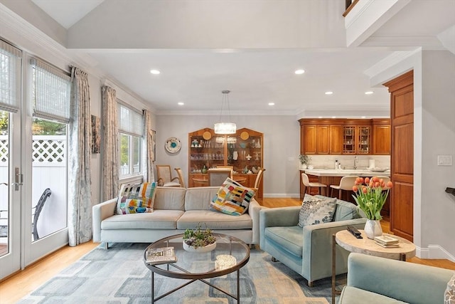 living area featuring light wood-type flooring, crown molding, recessed lighting, and baseboards