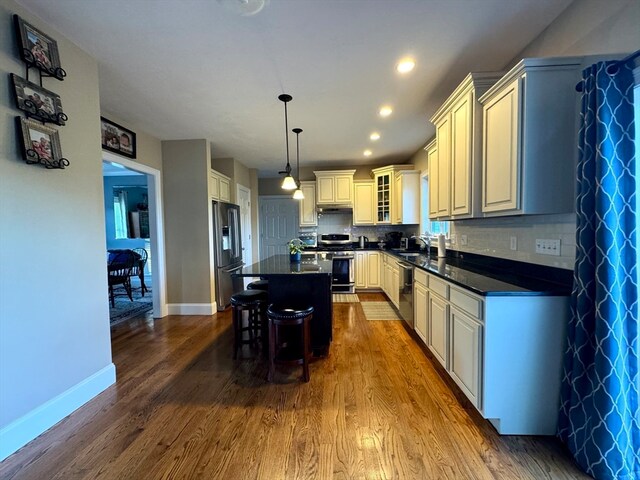 kitchen with stainless steel appliances, dark wood-type flooring, sink, decorative light fixtures, and a center island