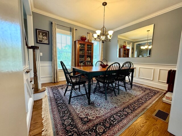 dining room with a notable chandelier, ornamental molding, and wood-type flooring