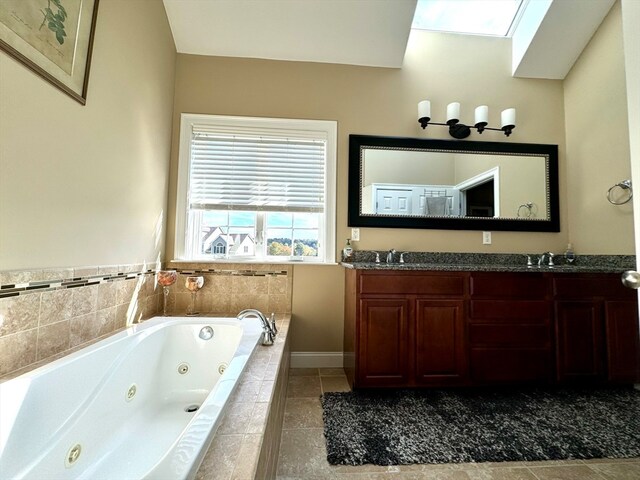 bathroom featuring vanity, a relaxing tiled tub, and a skylight