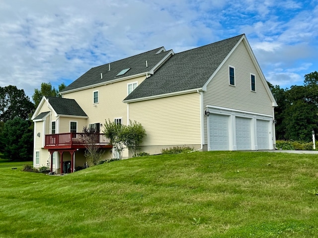 back of property featuring a yard, a deck, and a garage