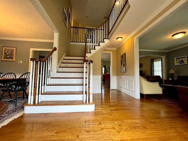 stairs with crown molding and wood-type flooring