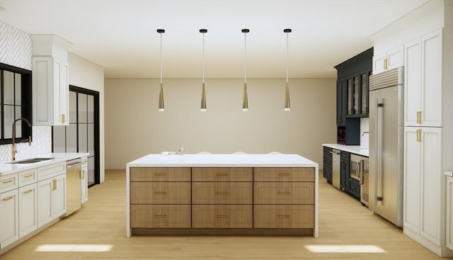 kitchen featuring appliances with stainless steel finishes, a sink, light wood-style floors, and a center island