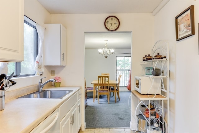 kitchen featuring pendant lighting, a notable chandelier, light carpet, sink, and white cabinetry