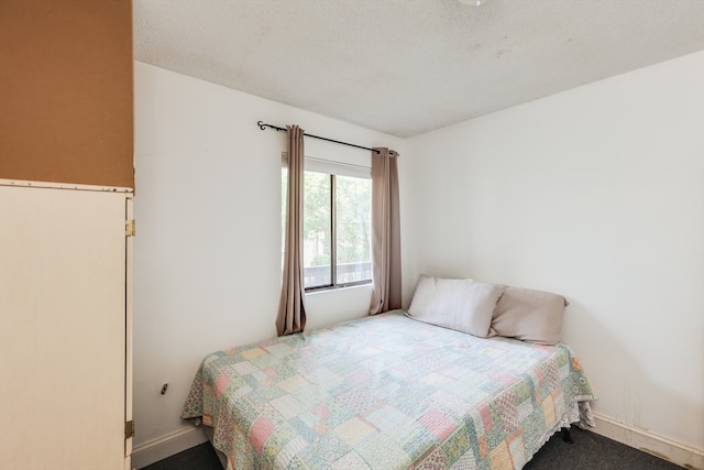 bedroom featuring dark carpet and a textured ceiling