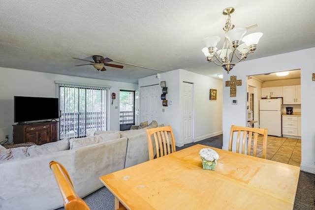 tiled dining area with ceiling fan with notable chandelier and a textured ceiling