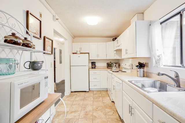 kitchen with white appliances, a wealth of natural light, sink, and white cabinets