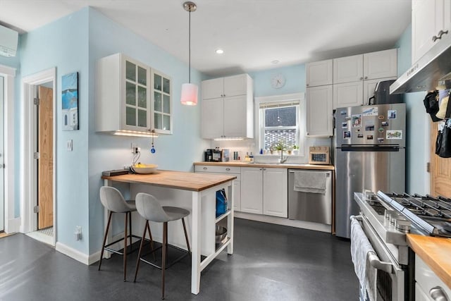 kitchen with appliances with stainless steel finishes, wood counters, a sink, white cabinets, and recessed lighting