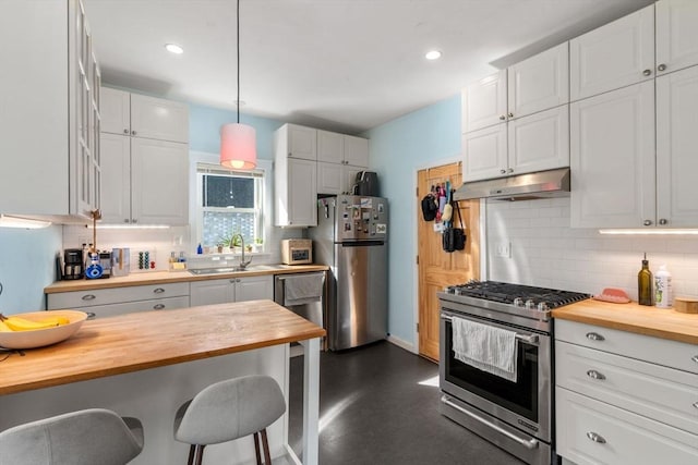 kitchen featuring butcher block counters, stainless steel appliances, a sink, under cabinet range hood, and backsplash