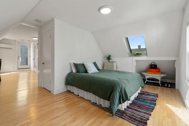 bedroom with light wood-type flooring, vaulted ceiling, a wall mounted AC, and baseboards