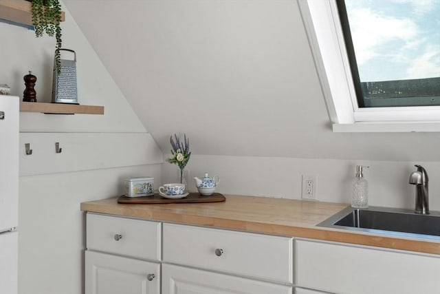 kitchen view of a sink, light countertops, and white cabinetry
