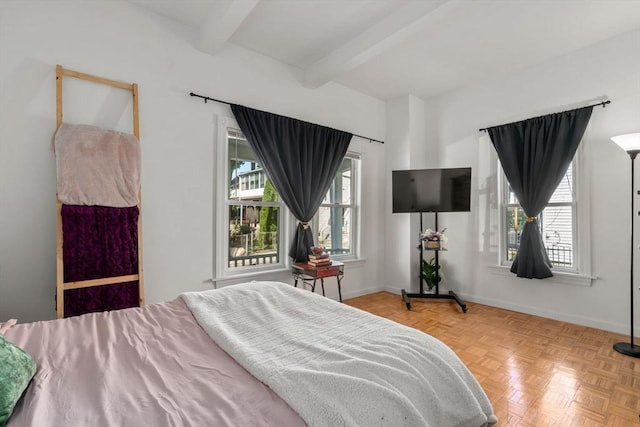 bedroom featuring multiple windows, beamed ceiling, and baseboards