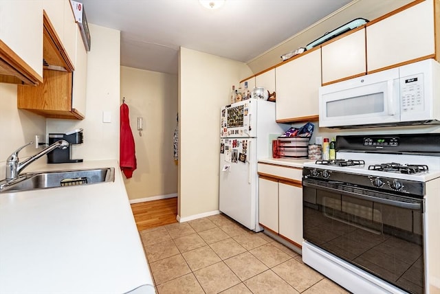 kitchen featuring light countertops, light tile patterned floors, white appliances, white cabinetry, and a sink