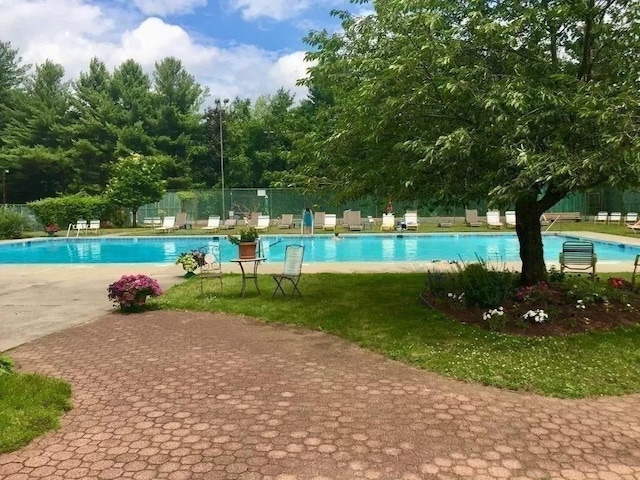 pool with a patio area, a lawn, and fence