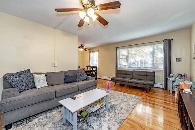 living area with light wood-style flooring, a baseboard radiator, and ceiling fan