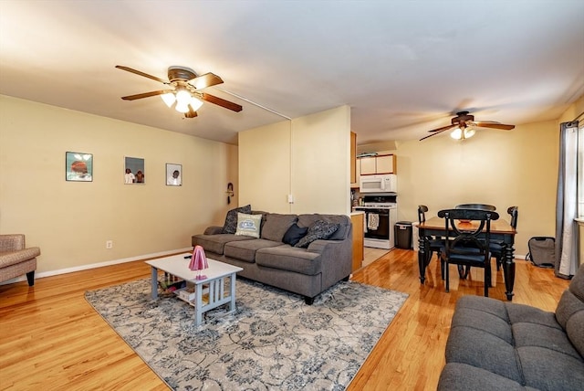 living area with light wood finished floors, baseboards, and a ceiling fan