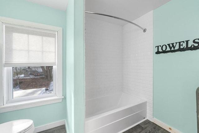 bathroom with wood-type flooring, toilet, and tiled shower / bath combo