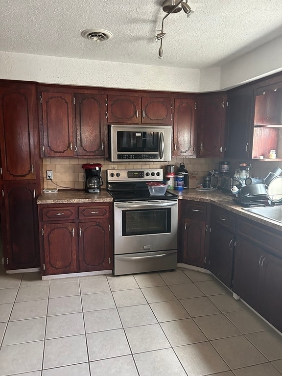 kitchen featuring light tile patterned floors, appliances with stainless steel finishes, a textured ceiling, and decorative backsplash