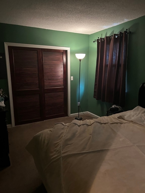 bedroom with carpet, a textured ceiling, and a closet