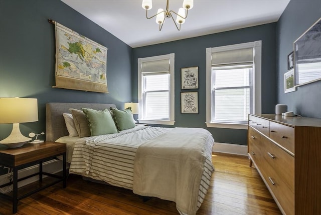 bedroom with a chandelier, wood-type flooring, and baseboards