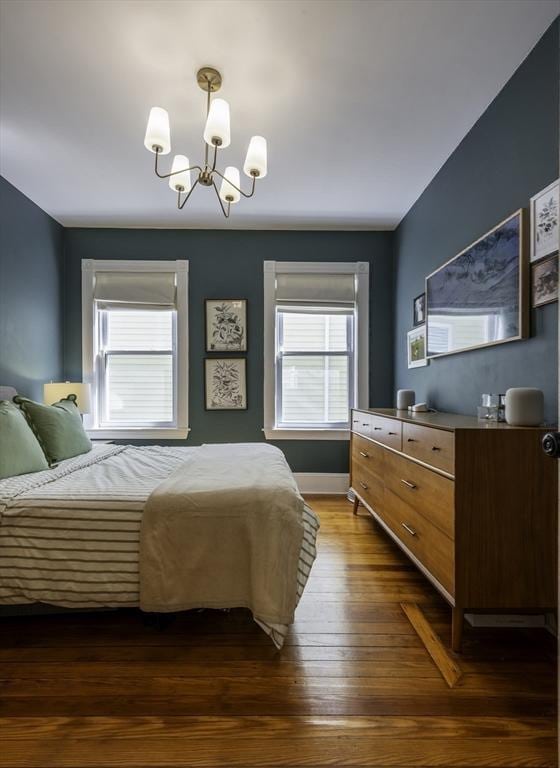 bedroom with a chandelier, multiple windows, dark wood-style flooring, and baseboards