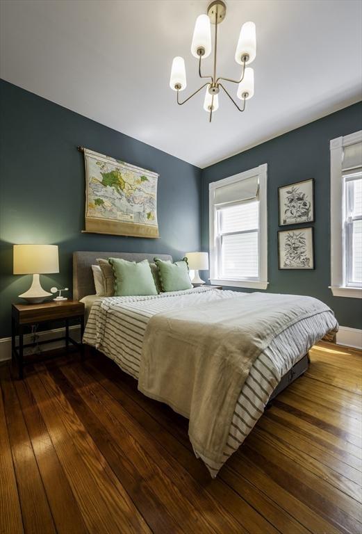 bedroom with a chandelier, hardwood / wood-style floors, and baseboards