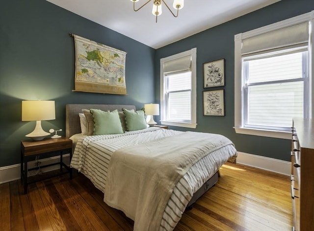 bedroom featuring wood-type flooring, baseboards, and a chandelier