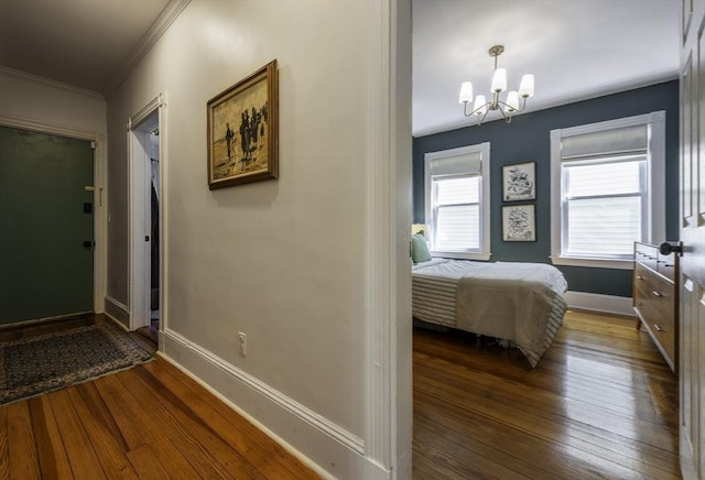 corridor with a chandelier, crown molding, dark wood-style floors, and baseboards