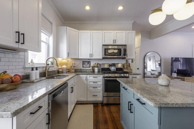 kitchen featuring appliances with stainless steel finishes, a sink, light stone countertops, white cabinets, and dark wood-type flooring