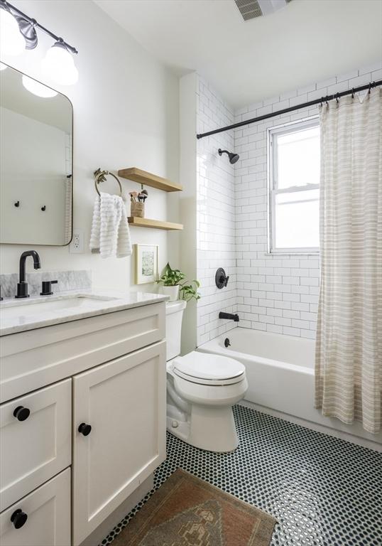 bathroom with shower / bath combination with curtain, toilet, and vanity