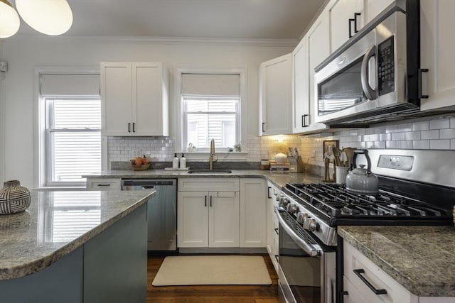 kitchen featuring stainless steel appliances, a sink, crown molding, dark wood-type flooring, and white cabinets