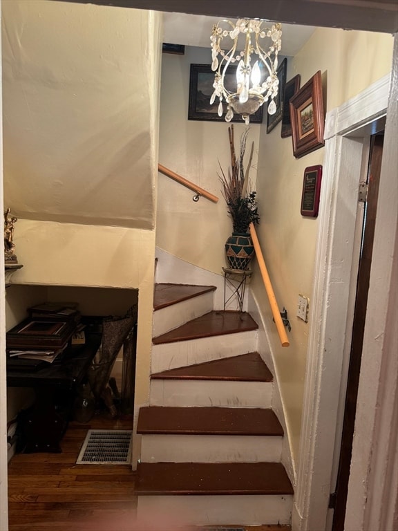 stairs featuring a chandelier and wood-type flooring