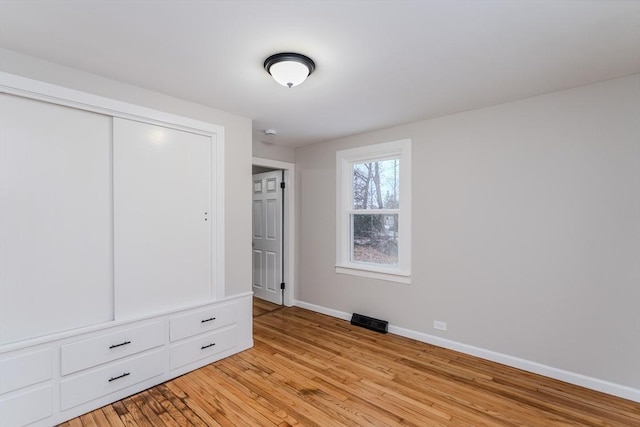 unfurnished bedroom with light hardwood / wood-style flooring and a closet