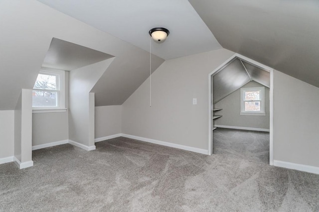 bonus room featuring a wealth of natural light, lofted ceiling, and light carpet