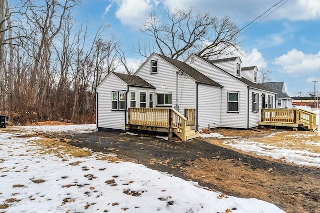 snow covered rear of property with a wooden deck