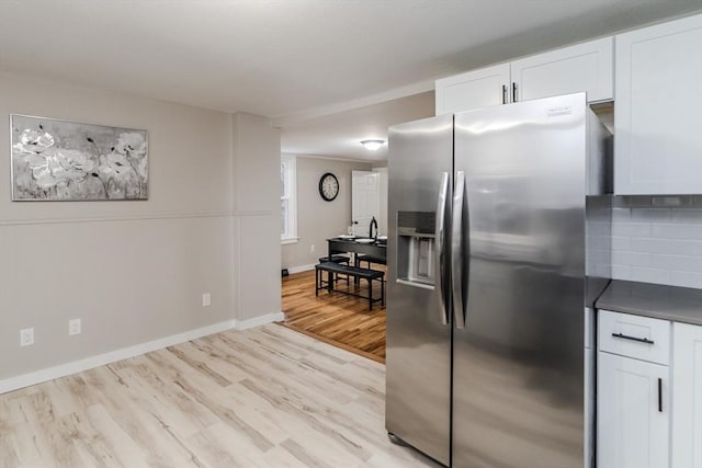 kitchen featuring decorative backsplash, white cabinets, light hardwood / wood-style floors, and stainless steel fridge with ice dispenser