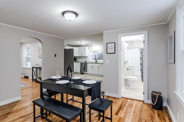 dining space featuring ornamental molding, sink, and light wood-type flooring