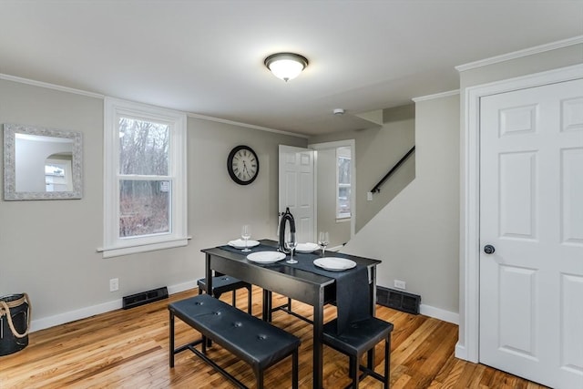 dining area with ornamental molding and light hardwood / wood-style flooring