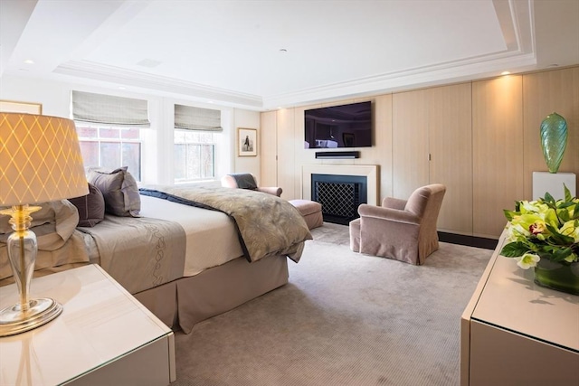 carpeted bedroom with a tray ceiling and wood walls