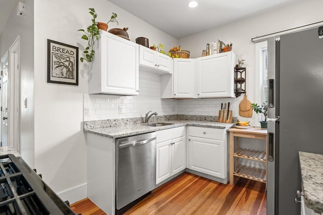 95 Child St Unit 2, Boston, MA 02130 - kitchen featuring stainless steel appliances, a sink, light wood-style flooring, decorative backsplash, and white cabinetry